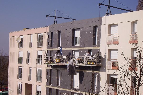 Chantier d'isolation thermique par l'extérieur : panneaux isolants en cours de pose sur la façade d'un bâtiment