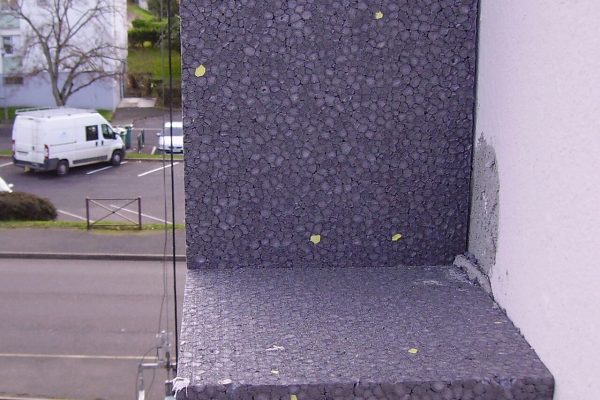 Panneaux isolants en polystyrène expansé appliqués sur la façade d'un immeuble en cours de rénovation énergétique